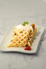 A plate of waffles with whipped cream and strawberries