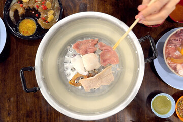 Woman eating thai bbq or moo ka ta.