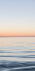 Obraz premium Calm ocean at sunset with soft pastel colors reflecting on the water