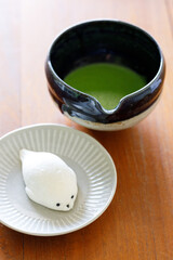 Cup of fresh matcha tea, green tea and Seal shape daifuku Japanese confectionery on wooden table.