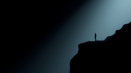 Silhouette of person on cliff edge, illuminated by light.