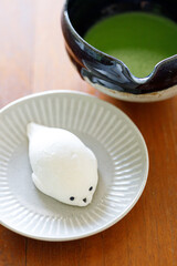 Cup of fresh matcha tea, green tea and Seal shape daifuku Japanese confectionery on wooden table.