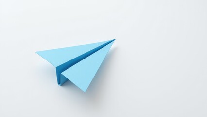 A light blue paper airplane rests gracefully on a pristine white surface, its delicate shadow stretching to the right, capturing a moment of serene flight and imagination in stillness