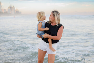 Mother holding son on the beach with Gold Coast city skyline in background