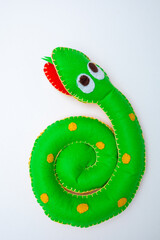 Chinese New Year 2025 - Year of Snake concept. Green snake toy with red cherry blossoms tree branch on a vibrant white background