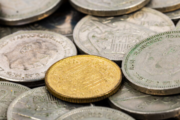 Close-up of Spanish pesetas from the Franco era, highlighting a golden coin in focus.