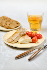 Freshly cooked fish served with cherry tomatoes and whole grain bread in a casual dining setting