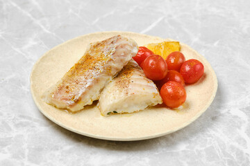 Grilled fish fillets served with cherry tomatoes on a neutral plate
