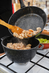 Fried chicken pieces are transferred to a pan