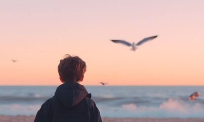 Fototapeta premium Little boy wearing a jacket and short hair looking at the sunset on the beach. Generative AI