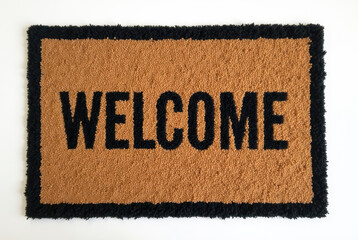 A welcome mat with 'Welcome' in black letters on a beige background