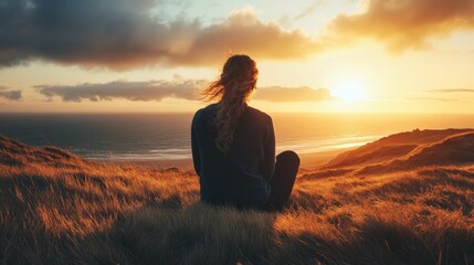 Silhouette of a woman watching sunset over the ocean from a clifftop