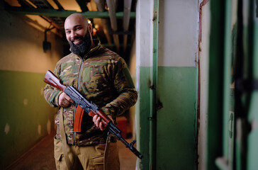 Portrait of the armed bearded man looking with a smiling face straight at the camera