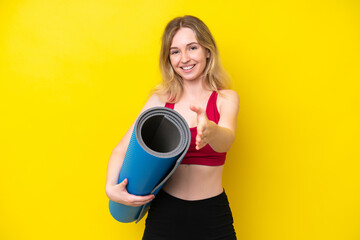 Young sport caucasian woman going to yoga classes while holding a mat isolated on yellow background shaking hands for closing a good deal © luismolinero