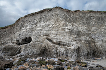 Rugged cliffs at Silverstrand Beach in Galway, Ireland, showcasing layers of sedimentary rock, with...