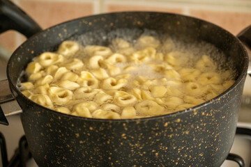 Raw Italian tortellini black pan in close-up