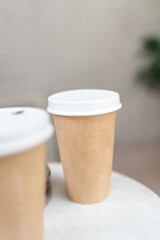 Brown paper coffee cup with white lid on top put on table