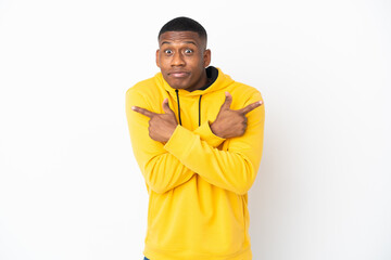Young latin man isolated on white background pointing to the laterals having doubts