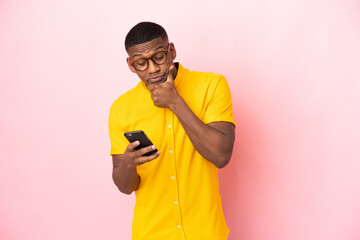 Young latin man isolated on pink background thinking and sending a message