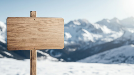 Naklejka premium Blank wooden signpost against a snowy mountain backdrop under a clear blue sky, invoking a sense of adventure.