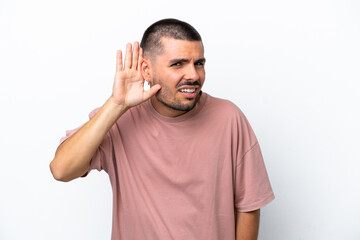 Fototapeta premium Young caucasian man isolated on white background listening to something by putting hand on the ear