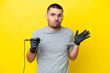 Tattoo artist caucasian man isolated on yellow background having doubts while raising hands