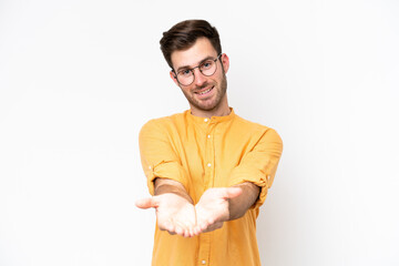 Young caucasian man isolated on white background holding copyspace imaginary on the palm to insert...