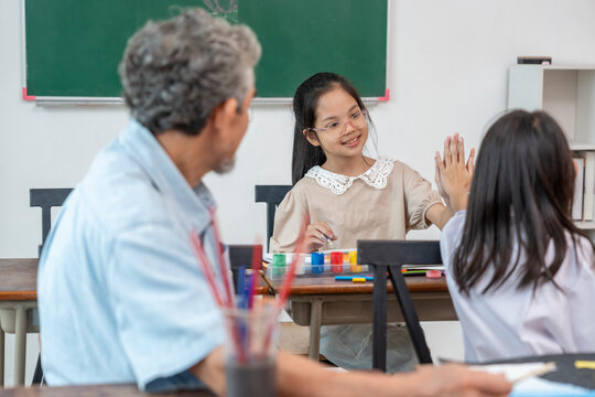 teen girls doing high five in class,enjoy studying  with a senior experienced teacher,elementary students learning new skill of painting during school break - Powered by Adobe