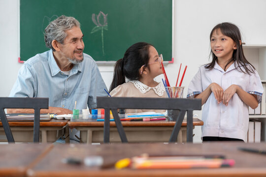 teen girls enjoy drawing watercolors with a senior experienced teacher,elementary students learning new skill of art during school break - Powered by Adobe