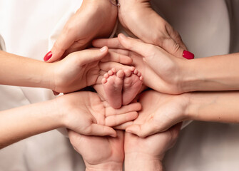 Family. Feet of a newborn in the hands of parents and brothers. Feet on a white background. Newborn feet.