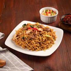 delicious fried noodles with vegetables pickles in a wood background
