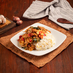 delicious indonesia nasi gila, a corn rice with a mix of sausages, meatballs and vegetables on a wooden background