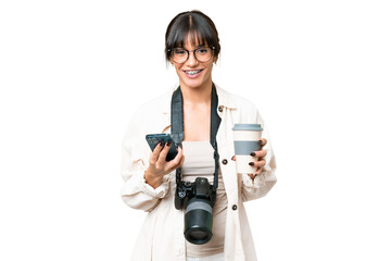 Fototapeta premium Young photographer caucasian woman over isolated chroma key background holding coffee to take away and a mobile