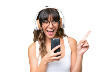 Young caucasian woman over isolated background listening music with a mobile and singing