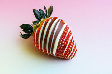 Gourmet chocolate-covered strawberry with decorative white drizzle and fresh green leaves on a pastel background