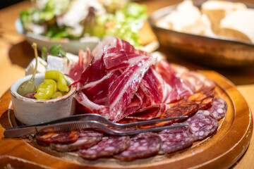 Cold cuts platter, variety of sliced meat and cheese with olives and nuts