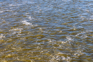 Rough flow of foaming water in the river, close-up, background