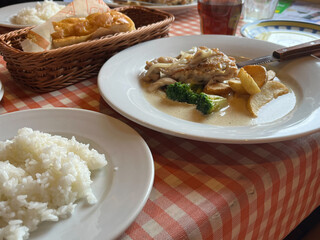 チキンのクリームソースとごはんとパンがのった食卓