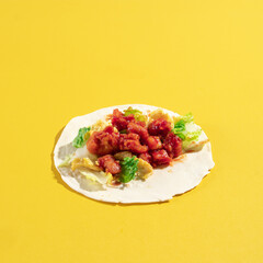 spicy fried chicken and vegetable on a flour tortilla wrap, on a yellow vibrant background