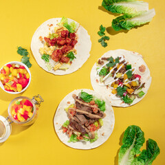 a variety of meat and vegetable on a flour tortilla wrap, on a yellow vibrant background