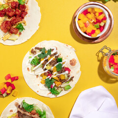 beef and mixed vegetable on a flour tortilla wrap, on a yellow vibrant background.