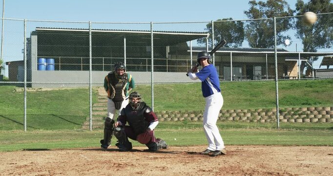 Male baseball players and umpire playing baseball, hitting ball and running on a pitch, slow motion