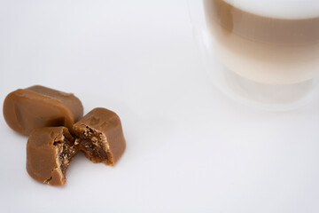 A glossy caramel candy in Mocha Mousse color next to a latte in a clear glass, showcasing a stylish color harmony.