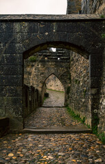 Aude Gate with stone arch and cobbled path inside the medieval fortress of Carcassonne on a cloudy day with the ground wet from the rain.
