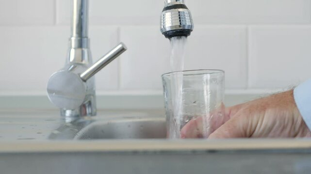 Thirsted Man Filling Up a Glass with Fresh Water from the Kitchen Water Tap.