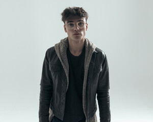 portrait of sexy young man in his 20s with glasses wearing black leather jacket