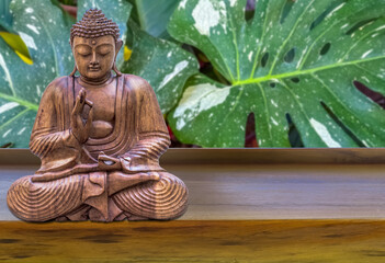 Bouddha sur table , fond philodendron  © Unclesam