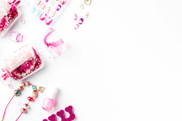 Pink accessories. Heart-shaped fluffy pen, colored false nails, candy-shaped containers with pink beads, nail polish bottles, a separator for pedicures, and jewelry items for girls.