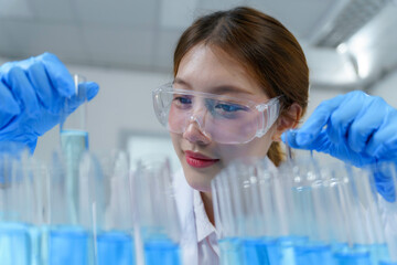 Scientist pouring blue liquid into test tubes in a laboratory setting, conducting experiments and...