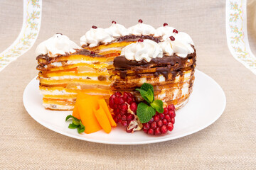 Colorful layered dessert with cream and fruits on a white plate